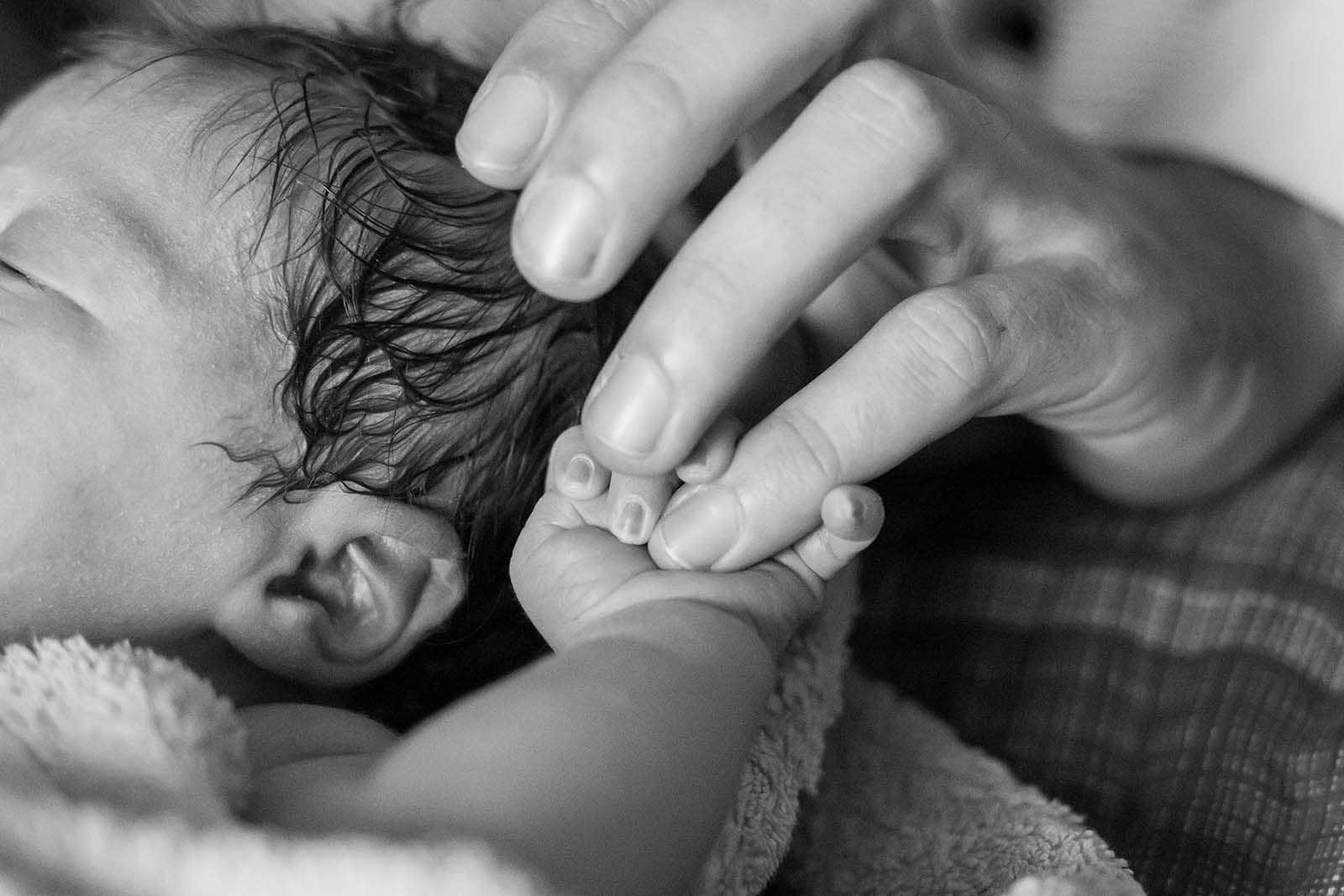 Ein Baby hält den kleinen Finger von der Mutter.